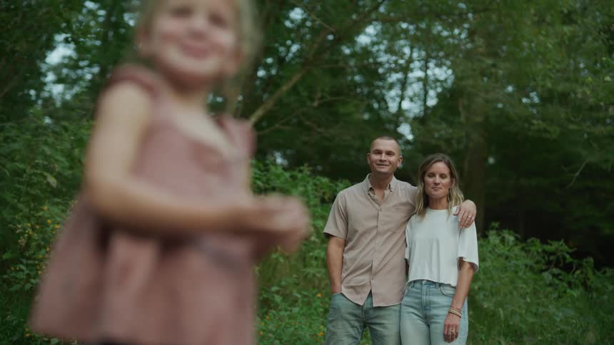 Parents act surprised when they see their little daughter throwing pebbles at a lake