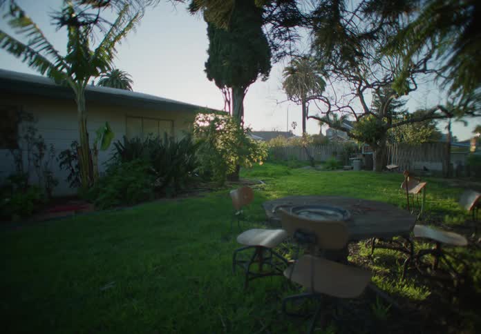 Wide shot of front yard with grass and outdoor furniture table and chairs sun is going down