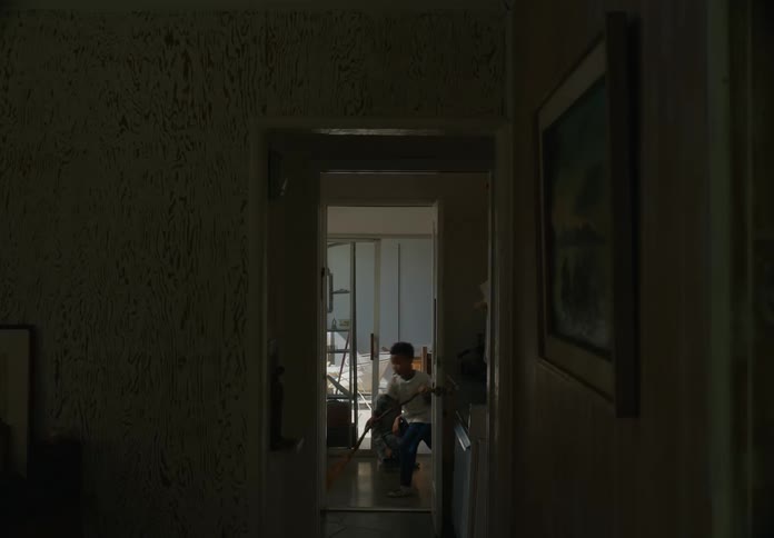 A youngster slowly sweeps the hardwood floor of the room that he is in