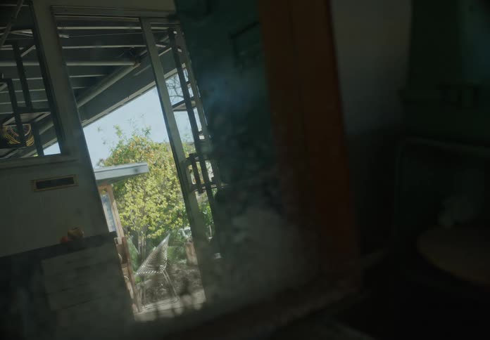 A dark room shows the outside from an open door