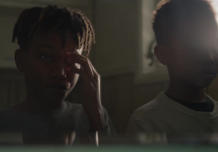 Two young boys look at their reflections in the mirror while grooming themselves
