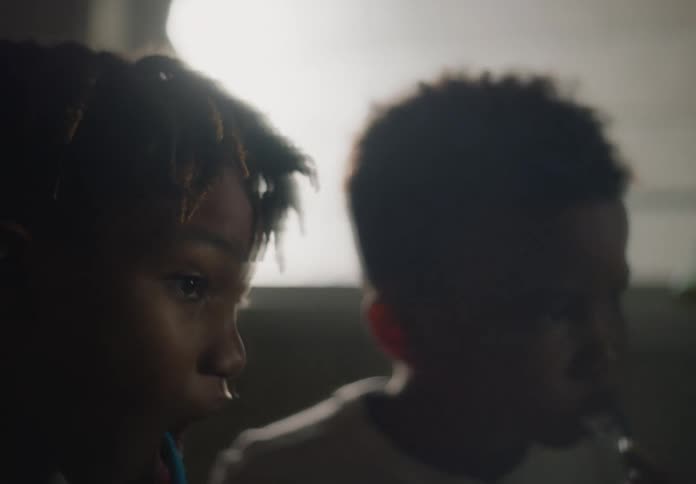 Two siblings brush their teeth in dimly lit bathroom