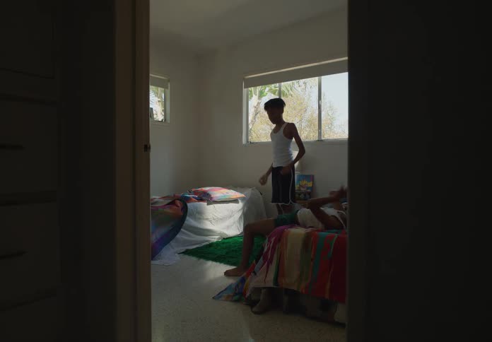 Two boys play in a bedroom under a window
