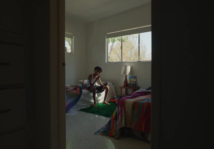 A boy in his bedroom holding a lit match then putting it out and throwing it down