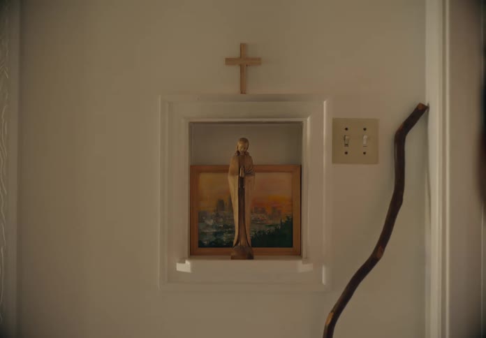 A child walks past the religious statue and cross