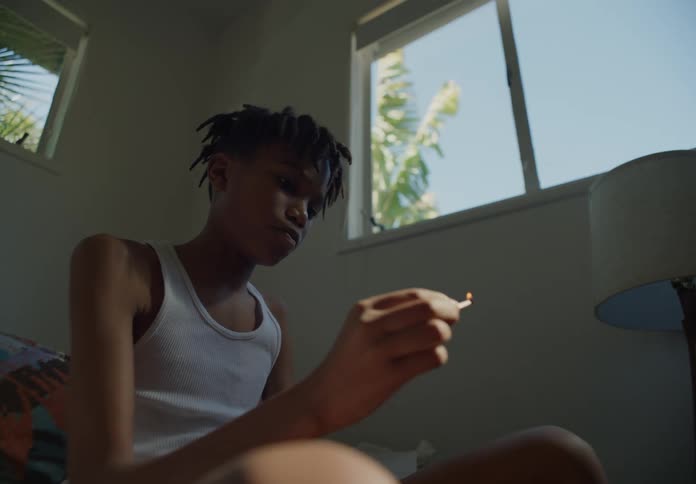 Bored young boy lights matches while sitting on a room at home next to a window