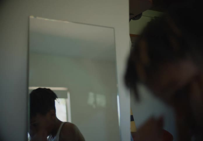 Young teenage boy shadow boxing in front of a mirror at home