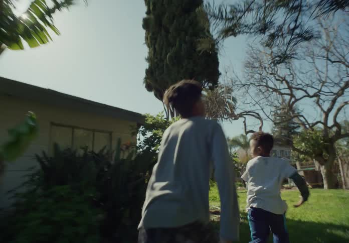 Two young boys run around and chase each other while in their yard