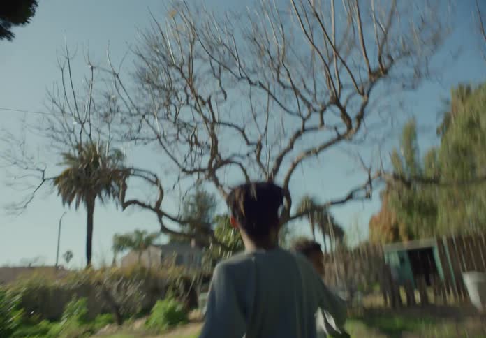 One boy chases another boy through their backyard