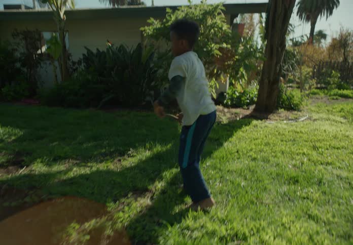 A boy walks barefoot on the grass in the backyard