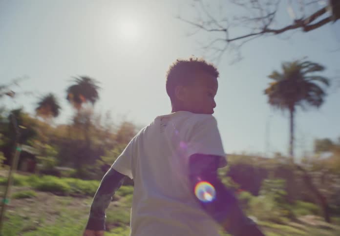 Two young boys are playing tag in the backyard of a house on a sunny day