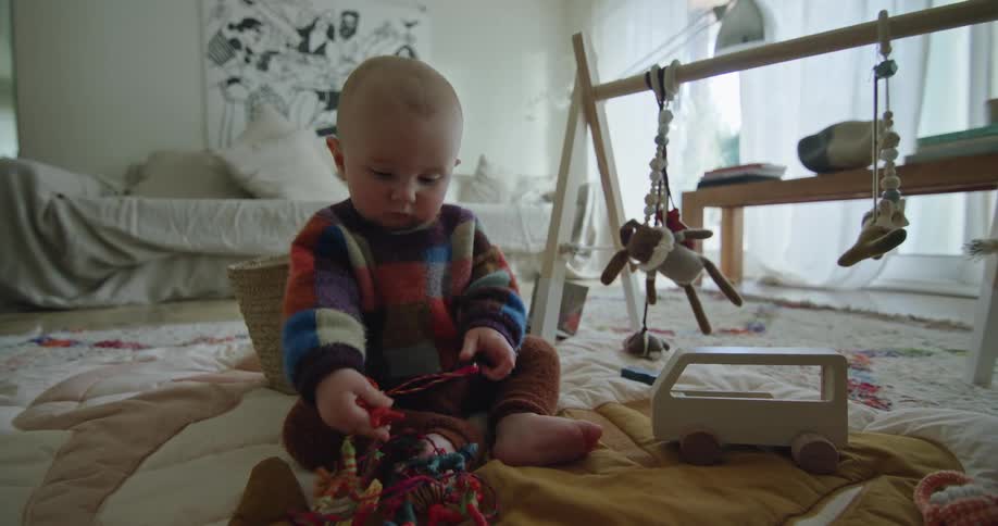 A baby is sitting on the living room floor playing with toys