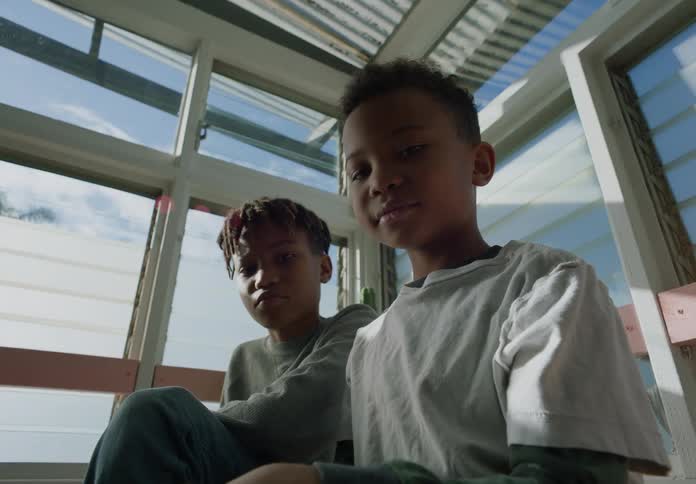A pair of boys look into the camera while sitting indoors during the day
