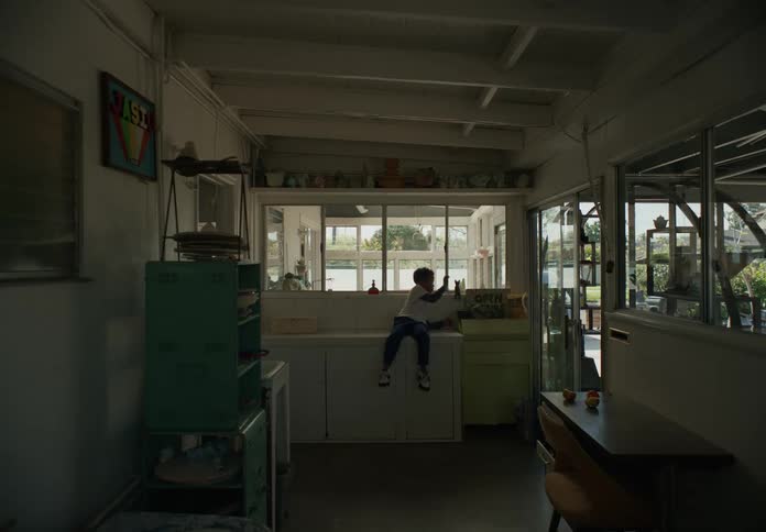 Boy sits on cabinet in utility room and plays with a toy