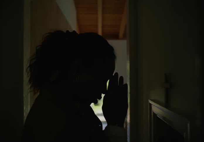 Silhouette of a young woman praying before leaving the room