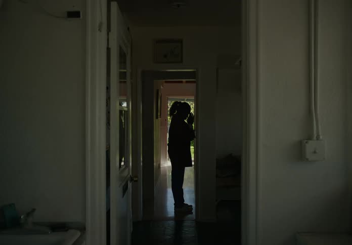 View from long hallway of mom walking through the open front door coming home from work