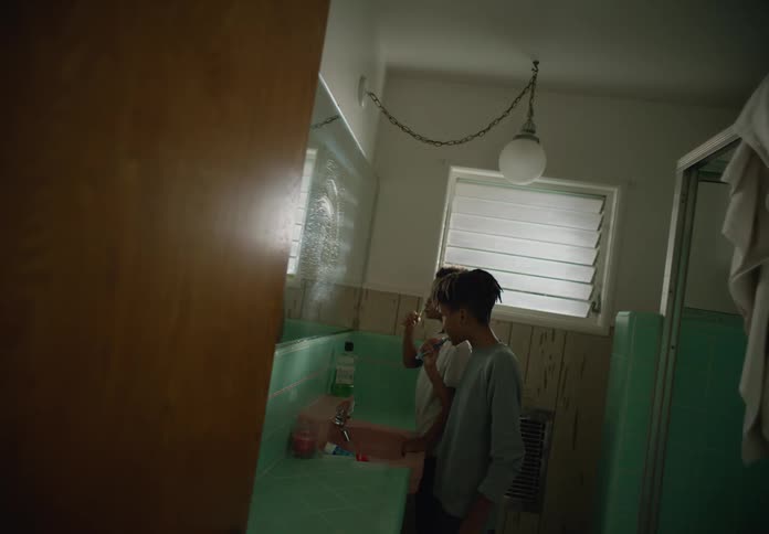 Brothers stand in bathroom brushing their teeth