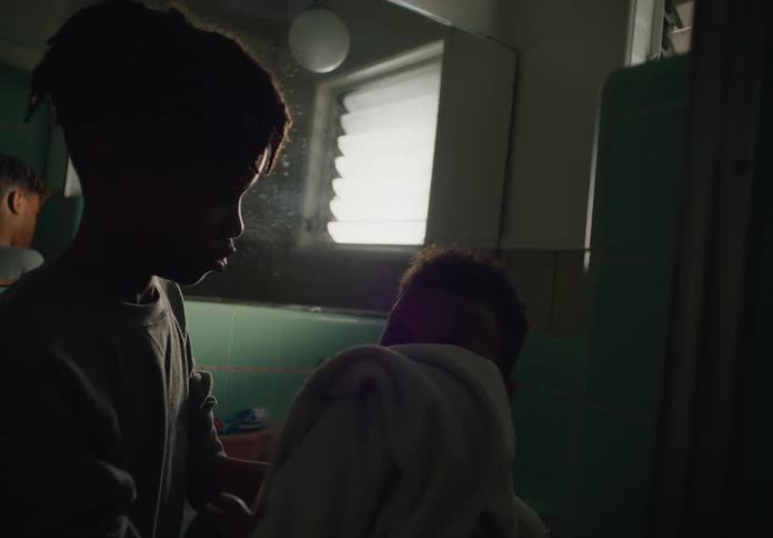 Older brother helps the younger one to dry her face with a towel in the bathroom at home