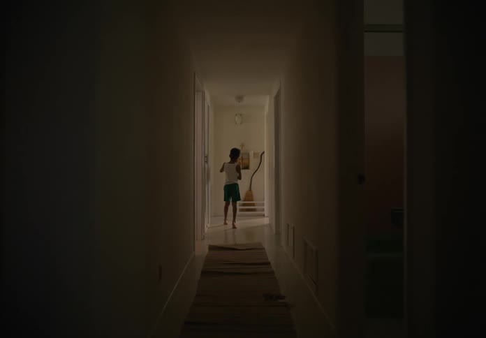 Young boy at home walking up and down long hallway with toy car