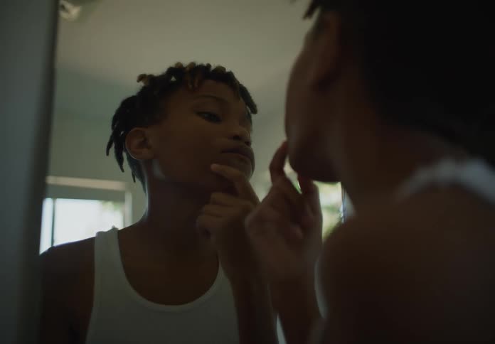 A young boy looks at his face in the mirror while checking for facial hair