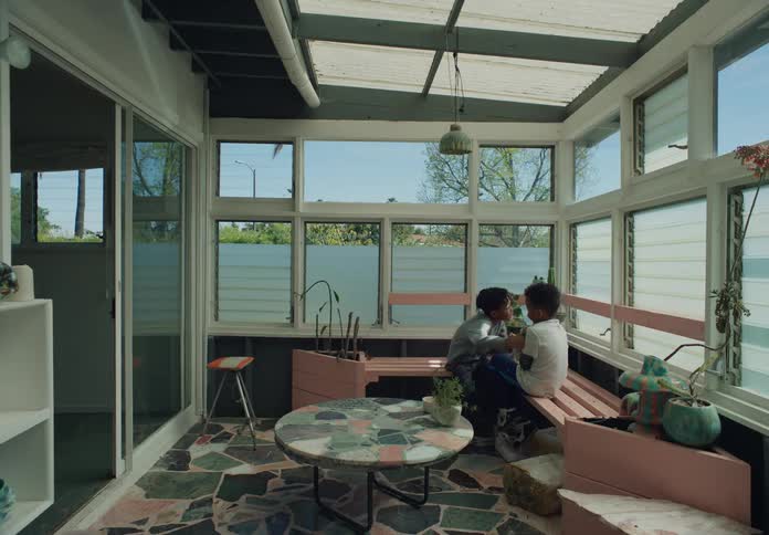 Older brother teases younger brother while they sit in sunroom
