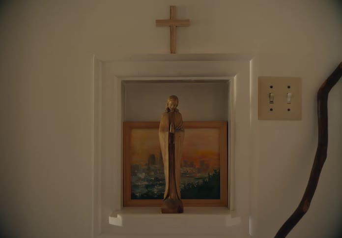 A religious statue is placed atop a shelf as a young boy walks past