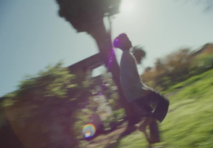 Two young brothers running and playing in front yard on the grass near swing in the sunshine