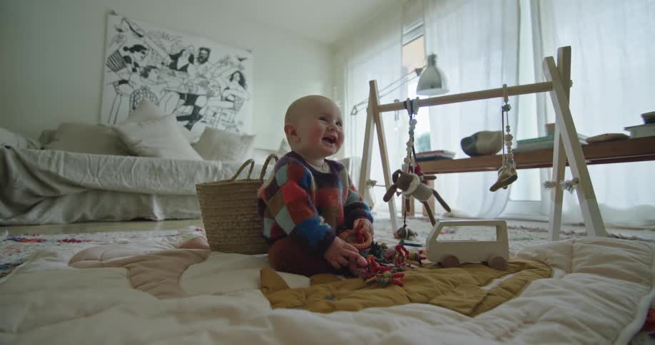 Young child sits on quilt on the floor and looks around