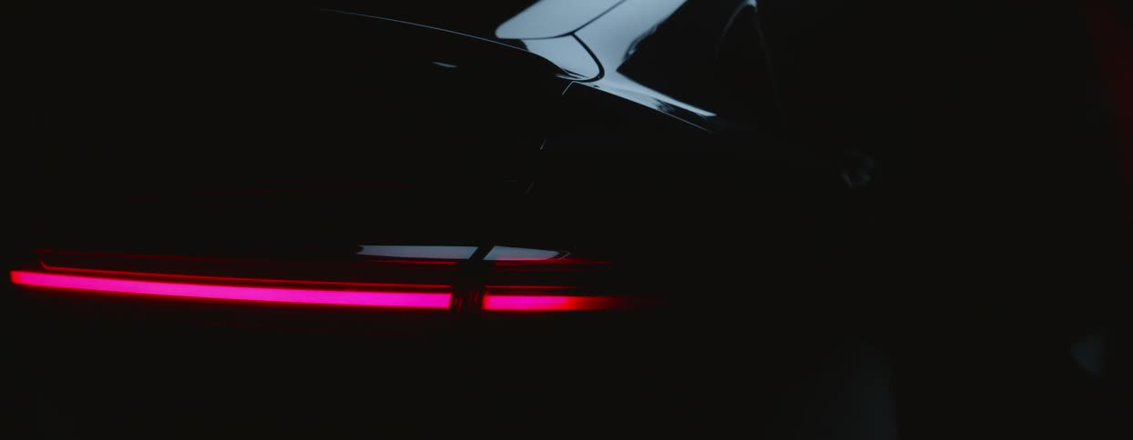 A dark colored vehicles tail lights flashing at night