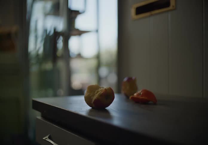 Two apple cores and some orange peels sitting on a kitchen table in the kitchen in the afternoon