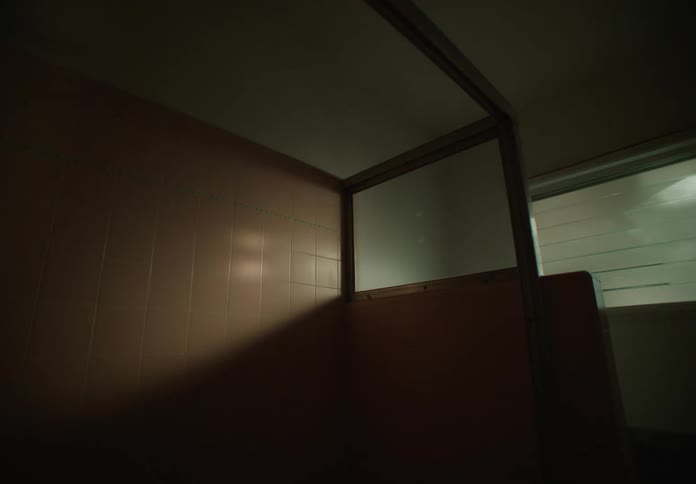 A room with pink tile on the wall and a framed in area as light casts shadows on the wall