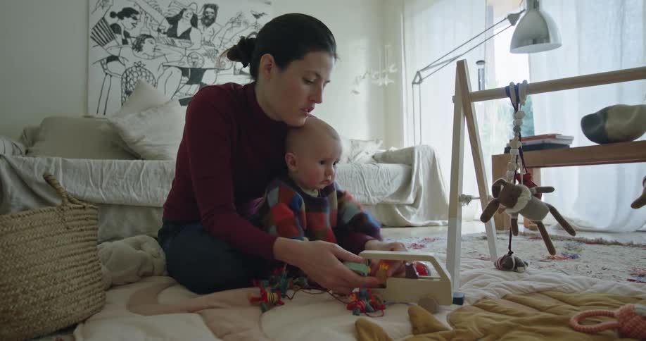 Mother and baby sitting on the living room floor playing with toys