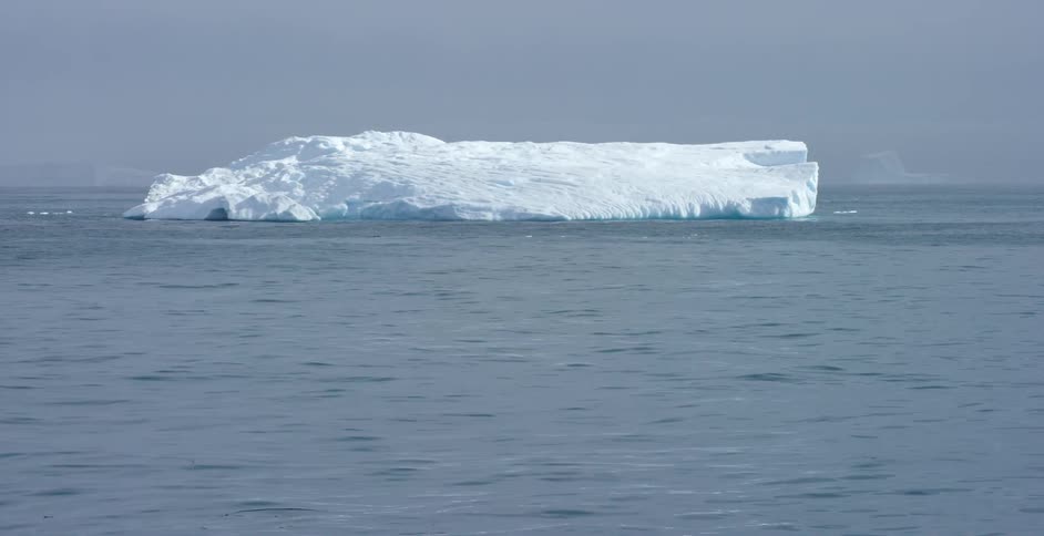A large iceberg sits in the water ahead