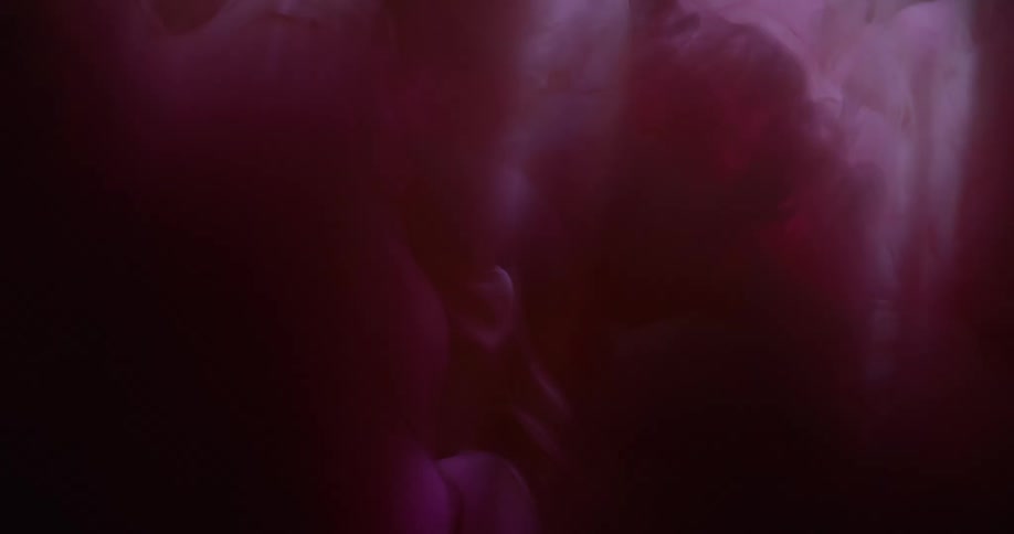 Shadows pass over a pink liquid suspended in a clear liquid