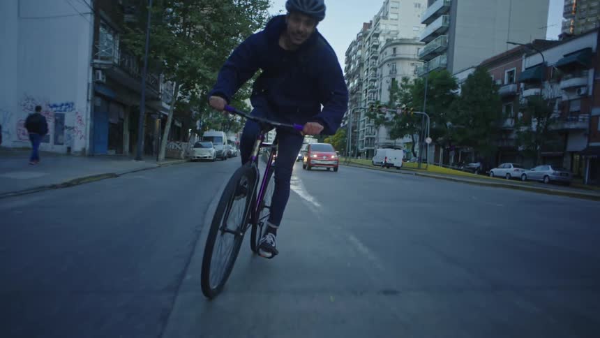 Male cyclist pedals along street smile on his face