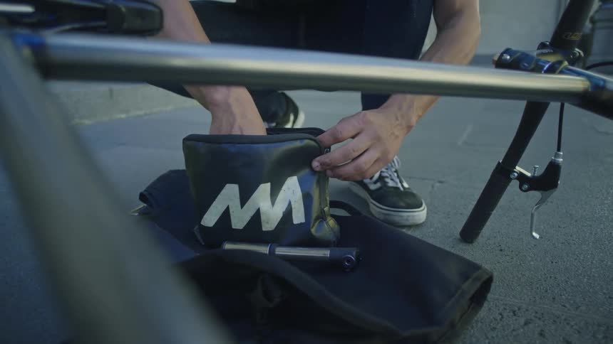 A man knelt down pulling tools out of a small black bag