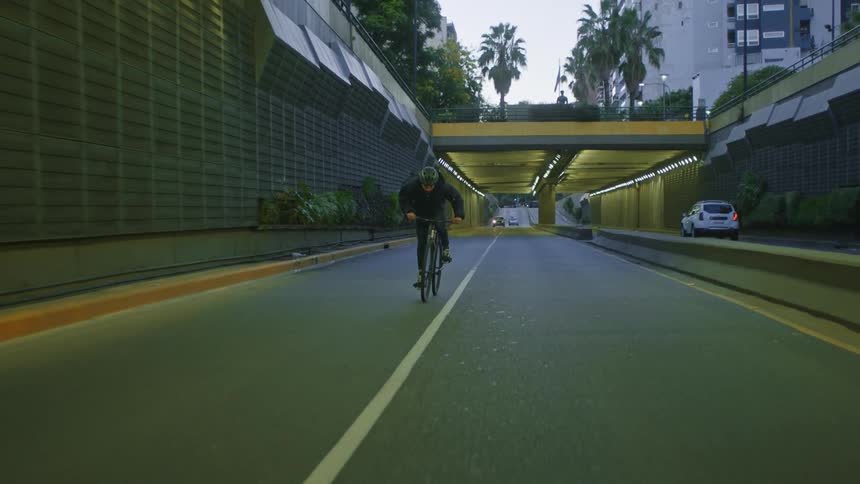 A man is riding his bicycle near the freeway