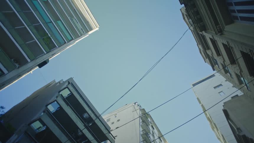 Lines cross between apartment buildings under a blue sky