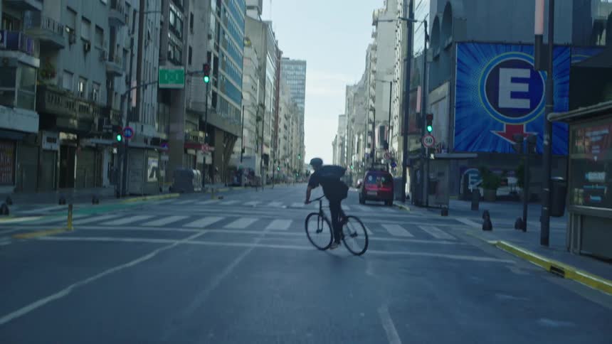 Man riding bike down city street urban downtown area but no cars weaving from side to side