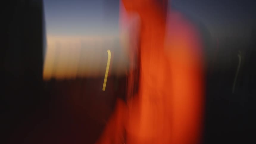 Shirtless man sitting on roof with red light on him motion blur and light streaking