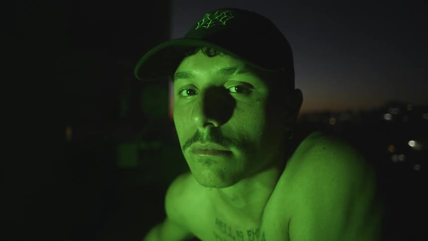 A man with the city lights behind him at night turns his head