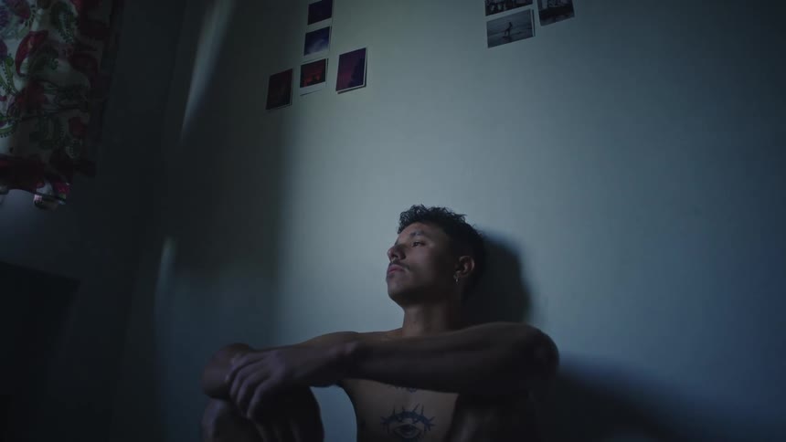 A man sits against the wall in his room