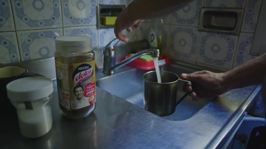 A man holds a mug under his kitchen faucet