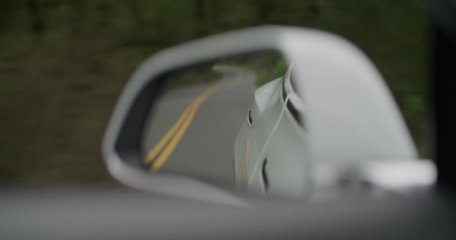 Closeup of drivers side rearview mirror of a car while driving