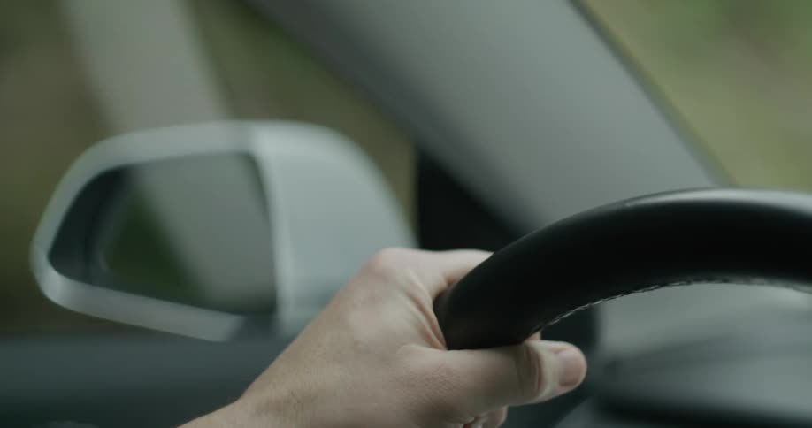 A person grips the steering wheel tightly while driving