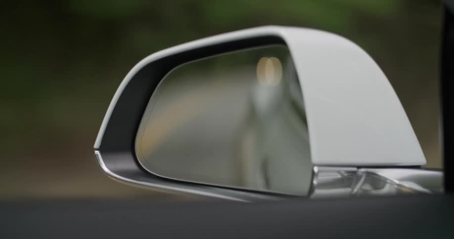 The mirror on a car as it drives down a road