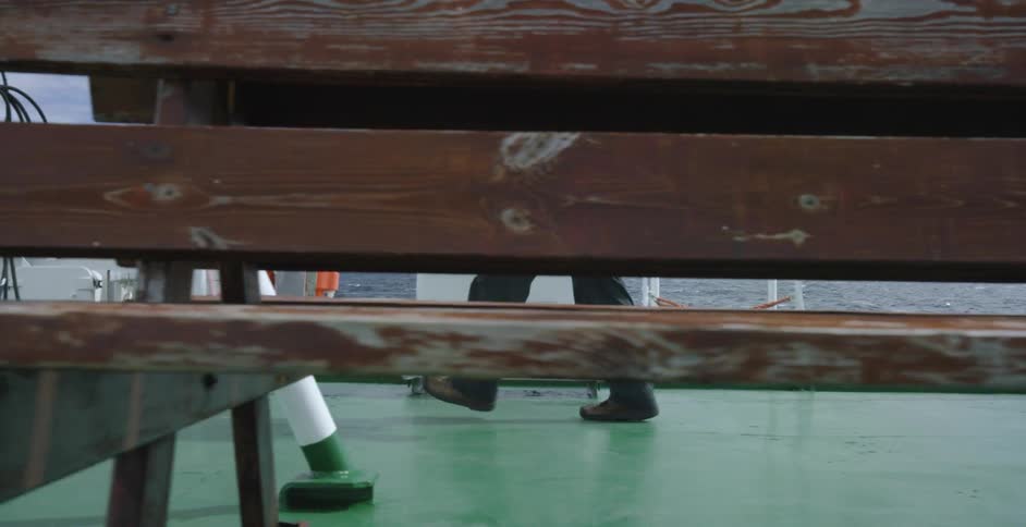A man carrying a camera walks across a ship