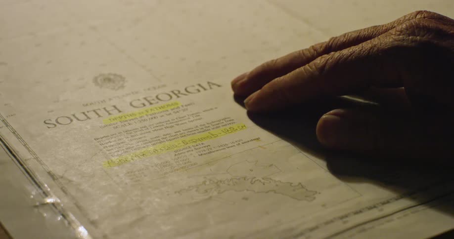 A man's hand moves across the edge of a map toward its legend