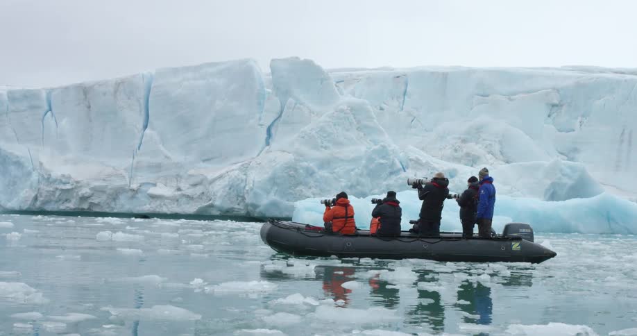 People are in a raft by an iceberg