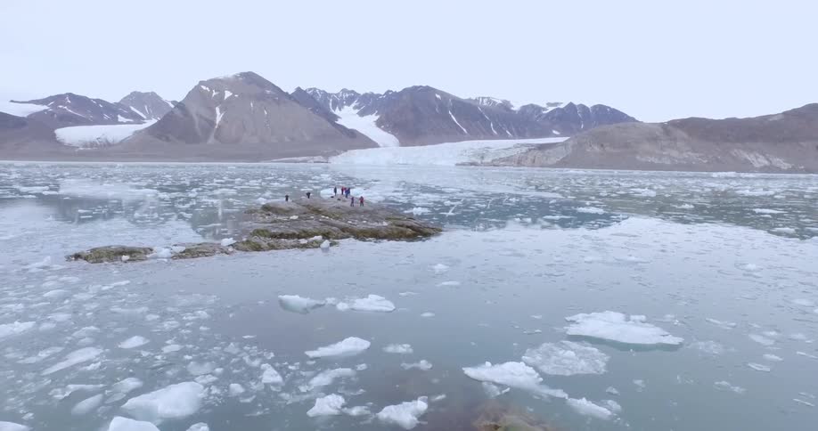 The water is filled with rocks and ice with people on one of the rocks